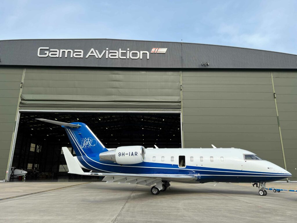 Private jet with open cabin door at an aviation facility outside hangar