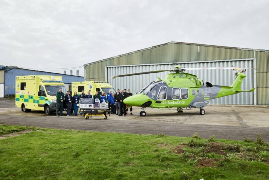Air ambulance crew stood in front of two ambulances and an air ambulance